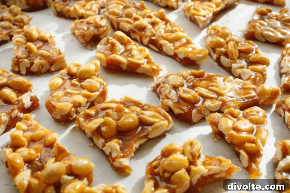 Crispy golden homemade peanut brittle scattered on a white surface