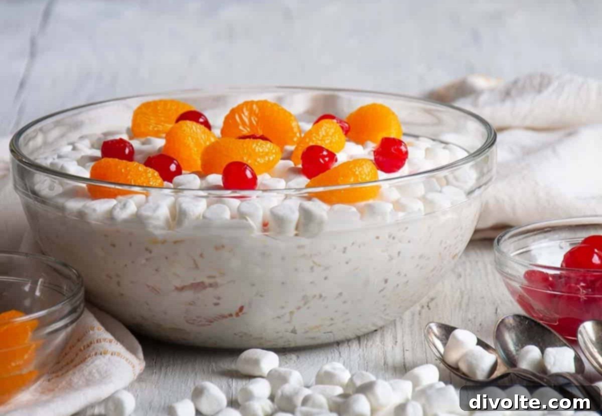 A large bowl of creamy Frog Eye Salad, showcasing pineapple tidbits, mandarin oranges, and mini marshmallows, ready to be served at a gathering.
