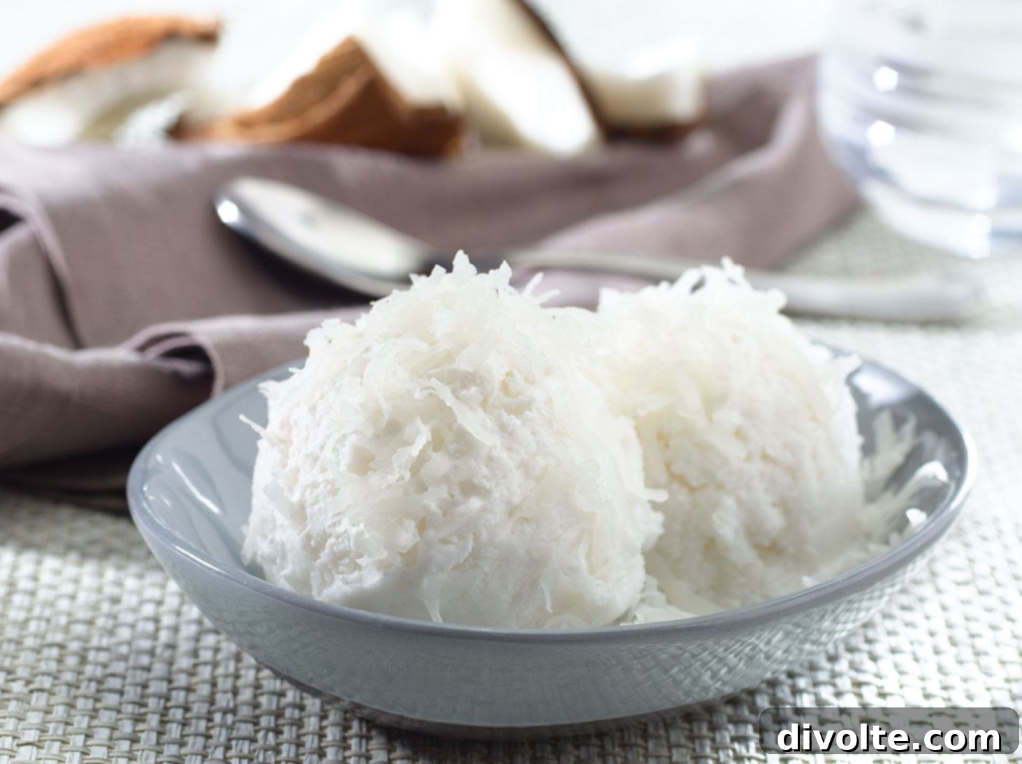 Freshly scooped coconut sorbet in a bowl, with lime and mint garnish.