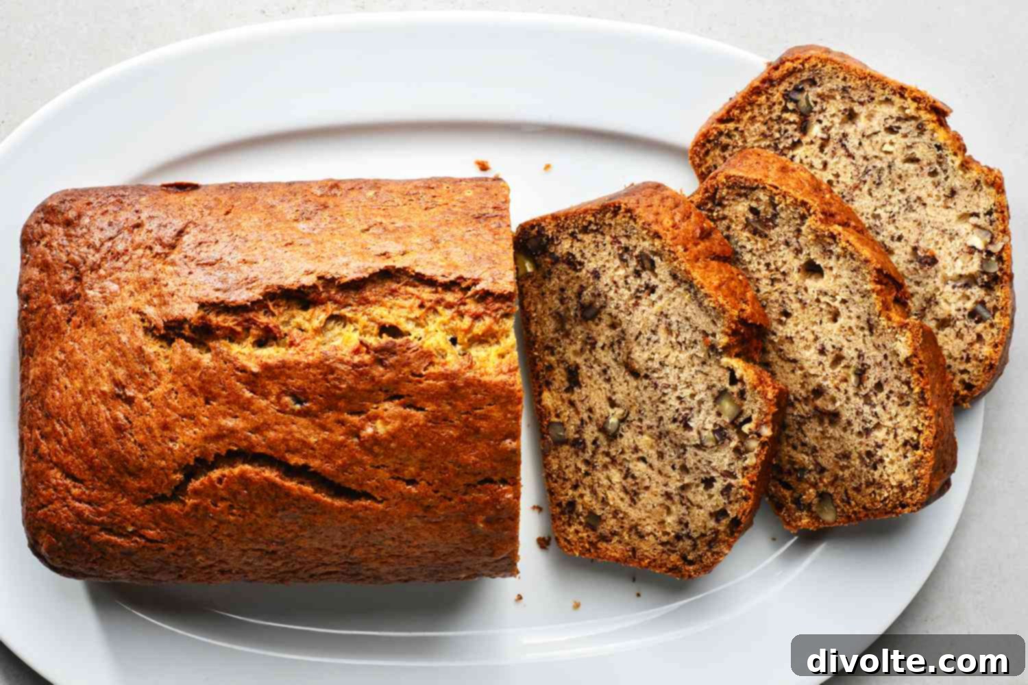 Sliced homemade banana walnut bread on a wooden board, showcasing its moist texture and crunchy walnuts.