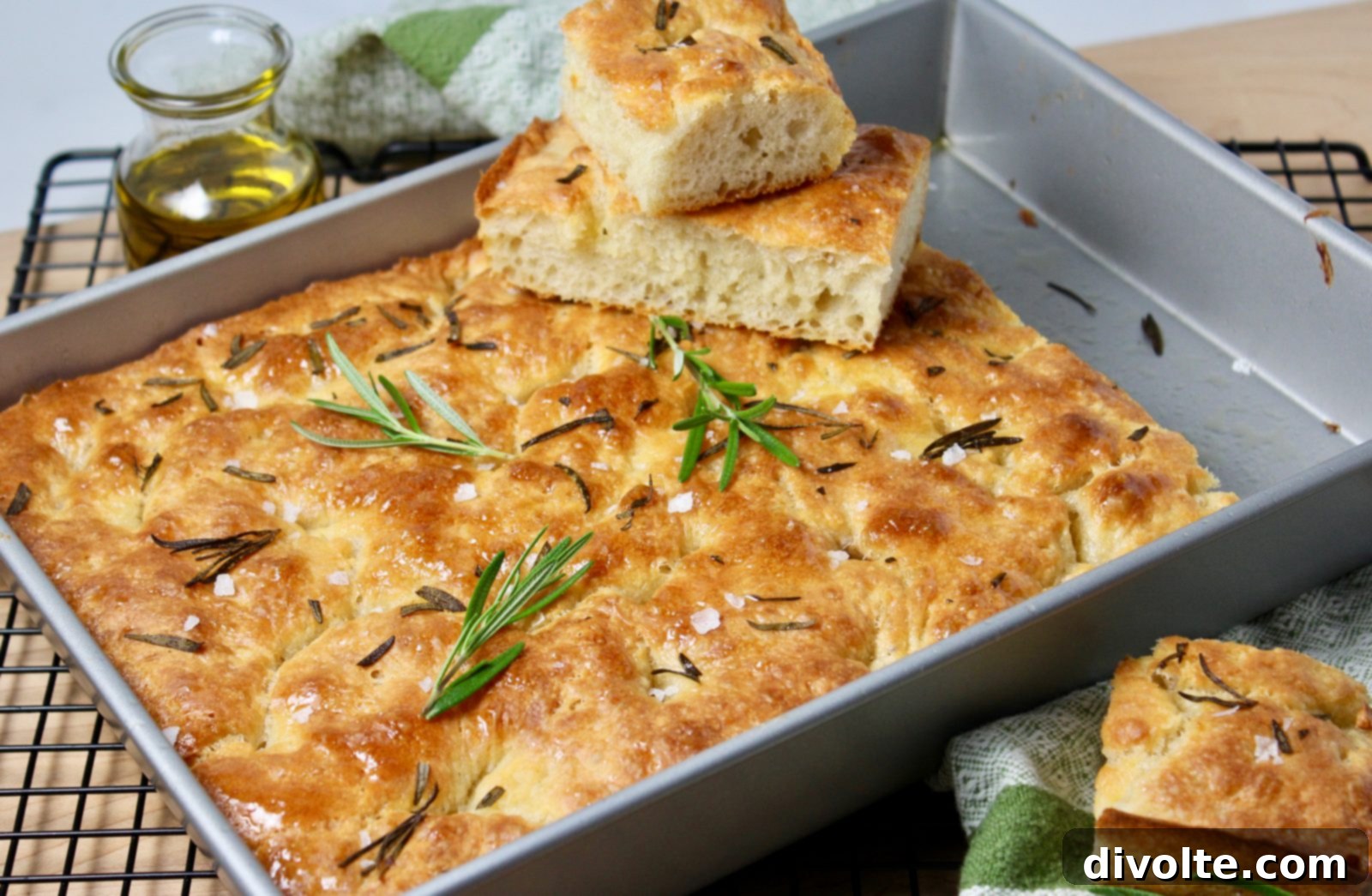 Close-up of freshly baked golden-brown focaccia bread, topped with rosemary and sea salt, ready to be sliced and served