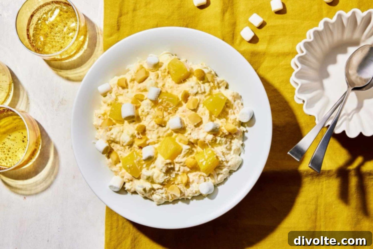 pineapple-fluff-recipe - A vibrant and fluffy pineapple dessert in a clear bowl, garnished with fresh mint.