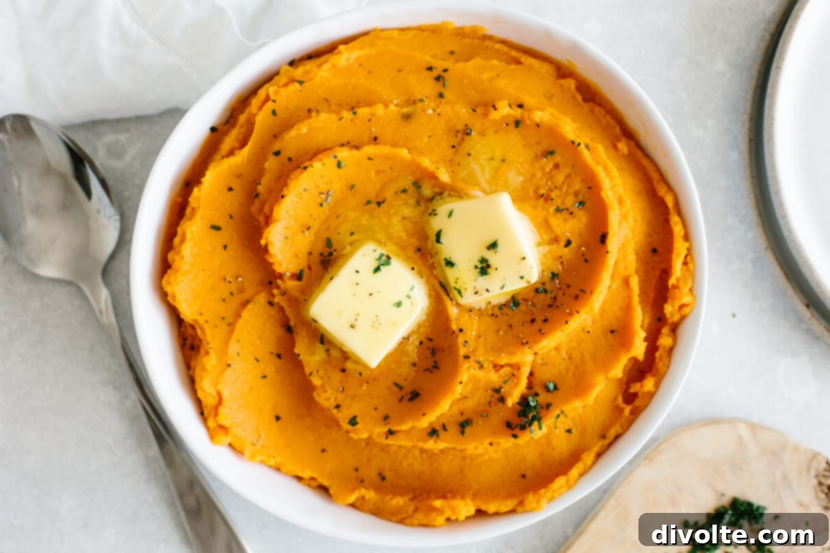 The Ultimate Sweet Potato Mash 2 Creamy sweet potato mash recipe, garnished with fresh herbs in a white bowl on a rustic wooden table.